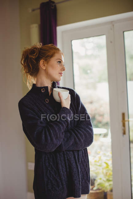 Задумчивая женщина пьет кофе на кухне дома — стоковое фото