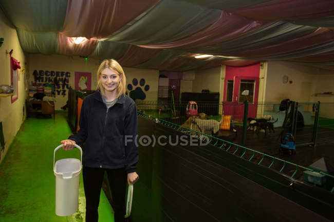 Portrait of woman carrying dog food in plastic container at dog care center — Stock Photo