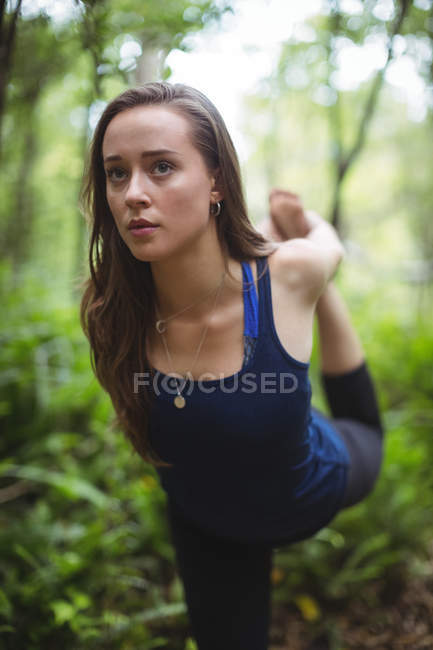 Mujer realizando ejercicio de estiramiento en el bosque - foto de stock