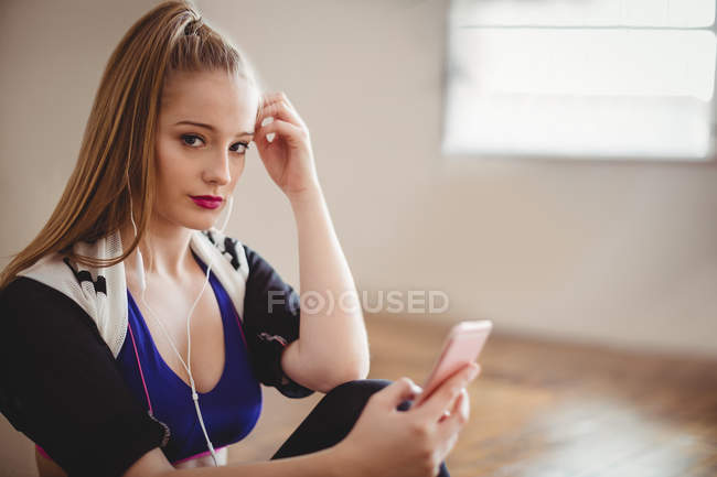Porträt einer blonden Frau, die im Studio Musik auf dem Handy hört — Stockfoto