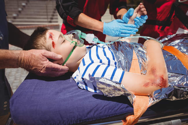 Les ambulanciers examinent un garçon blessé dans la rue — Photo de stock