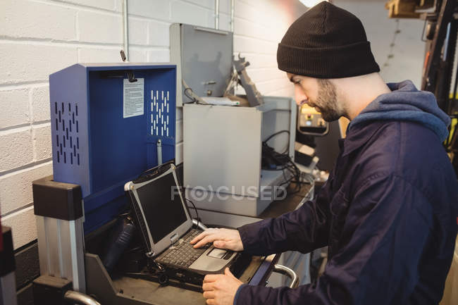 Mecánico usando el ordenador portátil en el garaje de reparación - foto de stock
