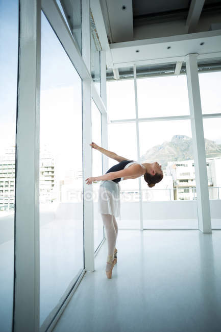 Балерина практикует балет у окна в студии — стоковое фото