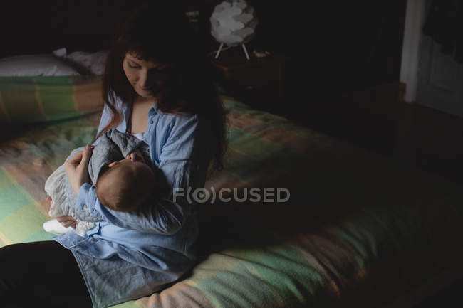 Mother breastfeeding infant baby in bedroom at home — Stock Photo