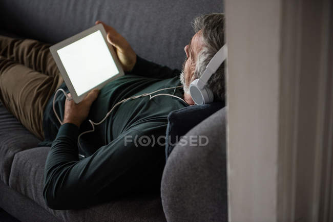 Mann hört zu Hause Musik auf digitalem Tablet — Stockfoto