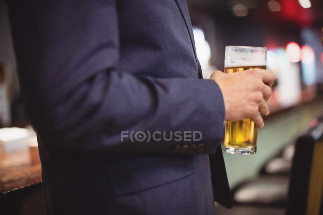 Средняя секция человека, держащего бокал пива в ресторане — стоковое фото