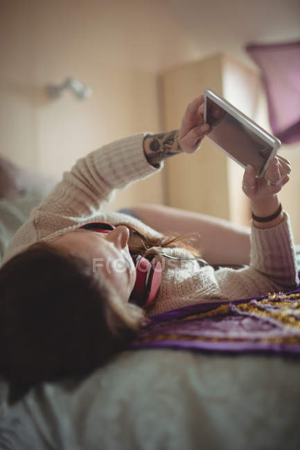 Frau nutzt digitales Tablet zu Hause im Bett — Stockfoto