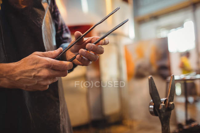 Close-up of glassblower holding tongs at glassblowing factory — Stock Photo