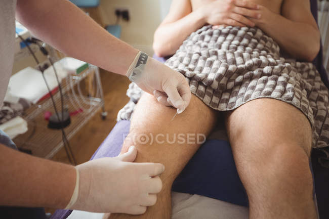 Fisioterapeuta realizando agulhas secas no joelho do paciente masculino na clínica — Fotografia de Stock