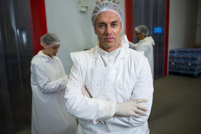 Porträt eines Metzgers, der mit verschränkten Armen in der Fleischfabrik steht — Stockfoto