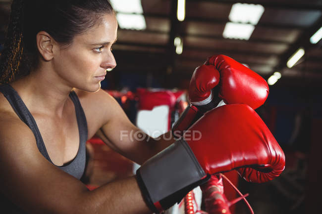 Mulher boxeadora atenciosa apoiada no ringue de boxe no estúdio de fitness — Fotografia de Stock