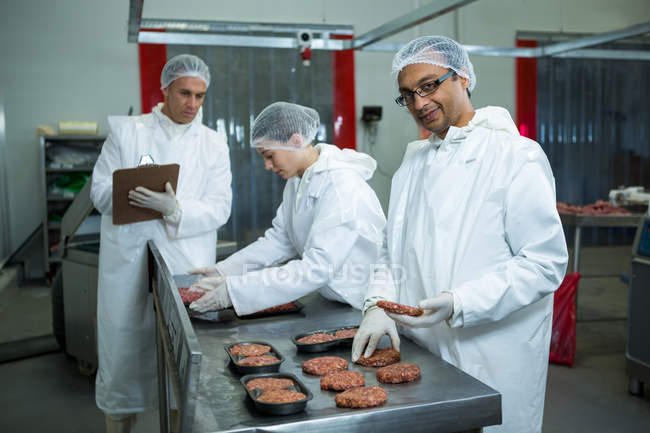 Macellai confezionamento polpette sul bancone in fabbrica di carne — Foto stock