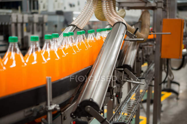 Processo di confezionamento di bottiglie di bevande arancioni in fabbrica — Foto stock