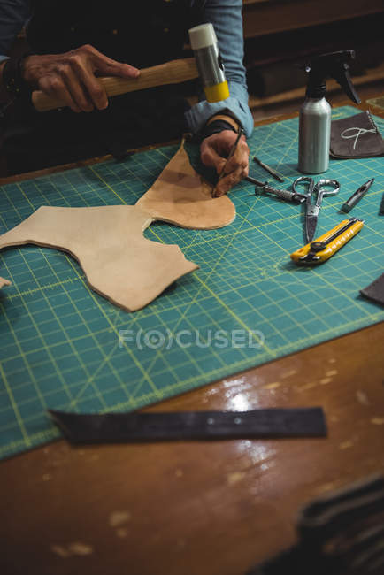 Mid-section of craftswoman hammering leather in workshop — Stock Photo