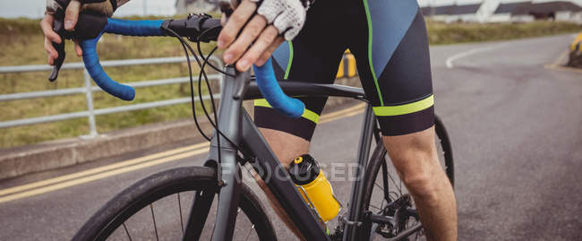 Mid-section of athlete riding bicycle on country road — Stock Photo