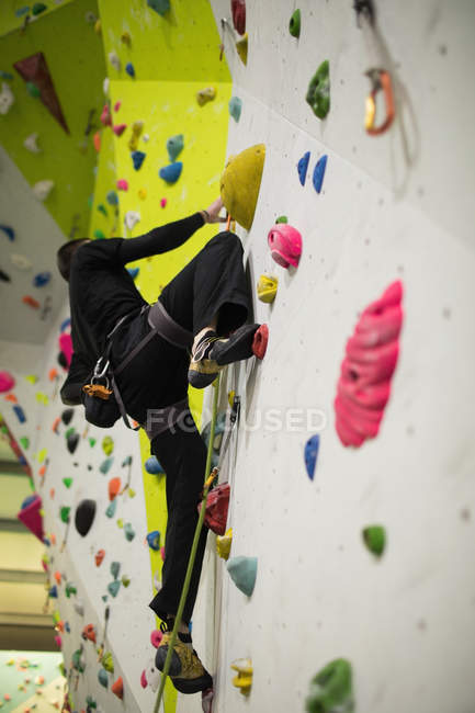 Человек, практикующий скалолазание на искусственной стене в спортзале — стоковое фото