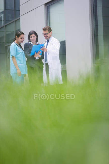 Médicos y enfermeras discutiendo sobre informe en instalaciones hospitalarias - foto de stock