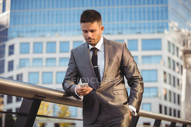Бізнесмен використовує мобільний телефон біля офісної будівлі — стокове фото