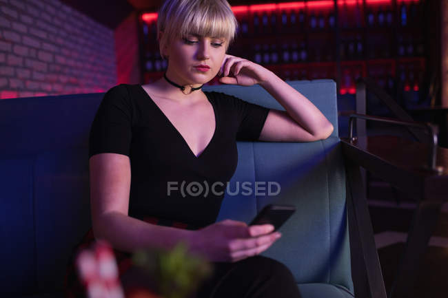Beautiful woman using mobile phone in bar — Stock Photo