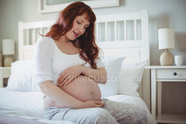 Thoughtful pregnant woman relaxing on bed in bedroom — Stock Photo