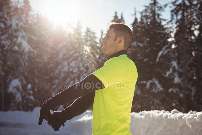 Продуманий чоловік розтягує руки в лісі взимку — стокове фото