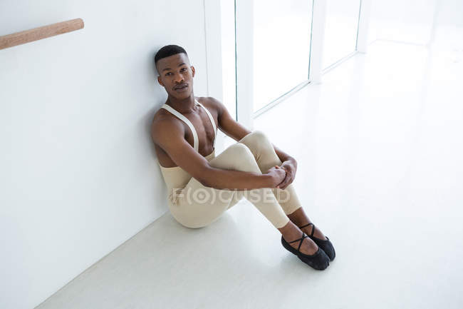 Thoughtful ballerino sitting on floor in the ballet studio — Stock Photo