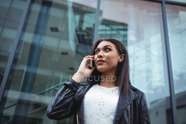 Mulher falando no celular fora do prédio de escritórios — Fotografia de Stock