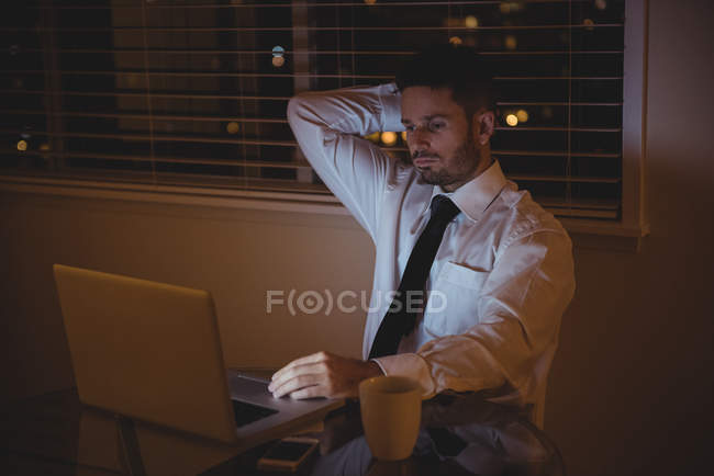 Напряженный бизнесмен использует ноутбук в гостиной на дому — стоковое фото