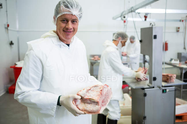 Porträt eines Metzgers, der Fleisch in Fleischfabrik hält — Stockfoto