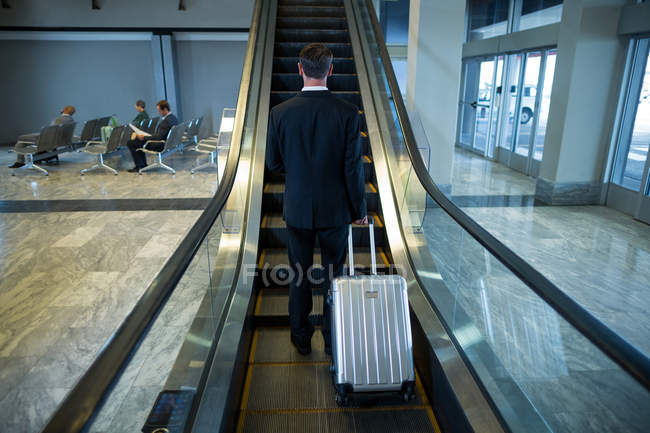 Visão traseira do empresário na escada rolante no aeroporto — Fotografia de Stock