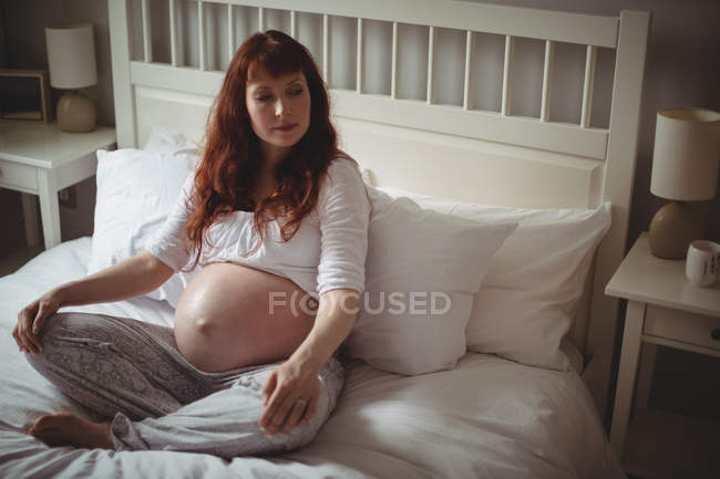 Mujer embarazada pensativo relajarse en la cama en el dormitorio - foto de stock