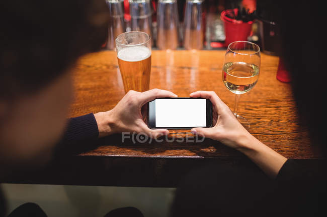 Gros plan d'un couple utilisant un téléphone portable au comptoir du bar — Photo de stock