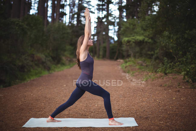 Жінка, що здійснює йога килимок Вправа в лісі — стокове фото
