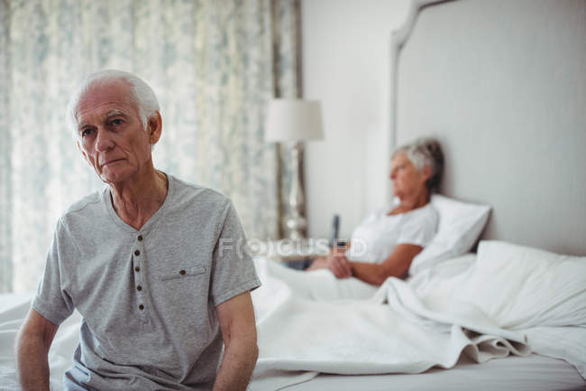 Worried and thoughtful senior man sitting in bed room — Stock Photo