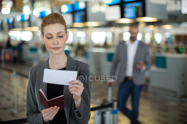 Mulher de negócios sorrindo verificando seu cartão de embarque no terminal do aeroporto — Fotografia de Stock