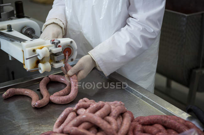 Butcher processing sausages at meat factory, cropped — Stock Photo