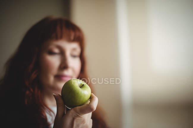Redhead woman holding green fresh apple in office — Stock Photo