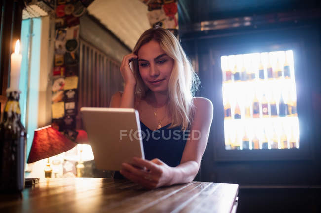 Красива усміхнена жінка використовує цифровий планшет в барі — стокове фото