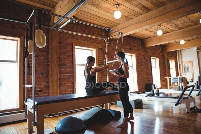 Treinador ajudando a mulher enquanto pratica pilates no estúdio de fitness — Fotografia de Stock