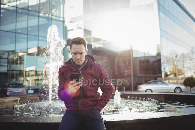 Executivo masculino usando telefone celular na frente do prédio de escritórios — Fotografia de Stock