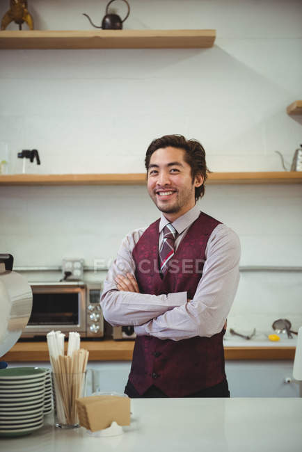 Porträt eines lächelnden Mannes, der mit verschränkten Armen in einem Café steht — Stockfoto