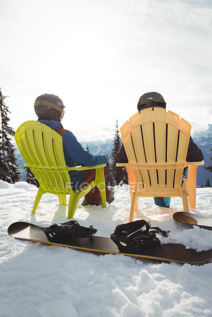 Rear view of couple sitting on mountain against sky during winter — Stock Photo