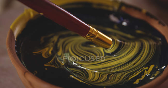 Крупный план чаши смешивания цветов с кистью в керамической мастерской — стоковое фото
