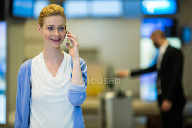 Empresária conversando no celular na área de espera no terminal do aeroporto — Fotografia de Stock