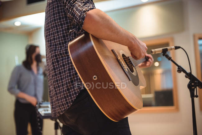 Середня частина людини, що грає на гітарі в музичній студії — стокове фото