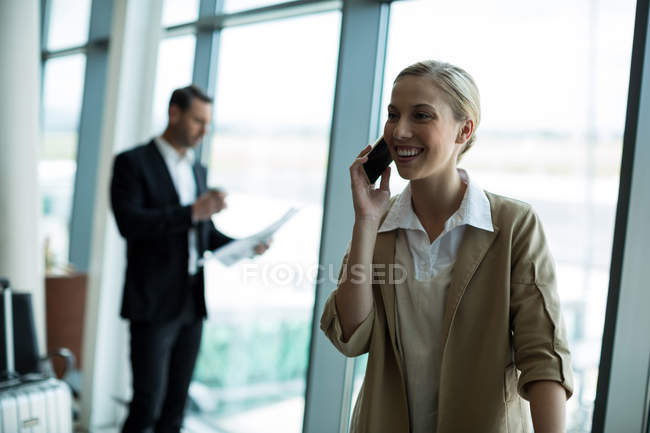Empresária falando no celular no aeroporto — Fotografia de Stock