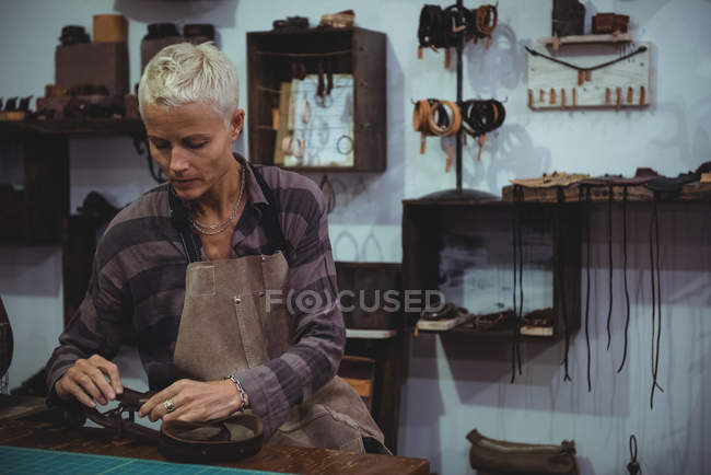 Ремесленница, работающая над куском кожи в мастерской — стоковое фото