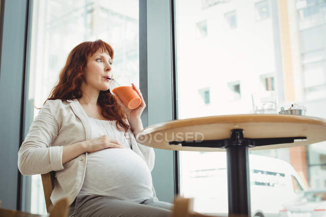 Femme d'affaires enceinte ayant jus de fruits dans la cafétéria de bureau — Photo de stock