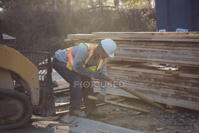 Construction worker arranging timber at construction site — Stock Photo