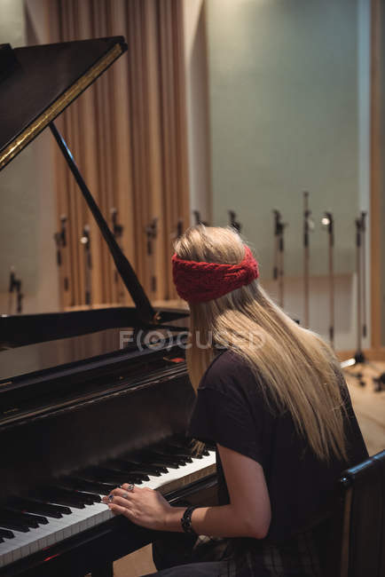 Rear view of woman playing a piano in music studio — Stock Photo